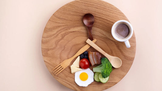 Wooden plate of food with utensils split into three sections to illustrate intermittent fasting