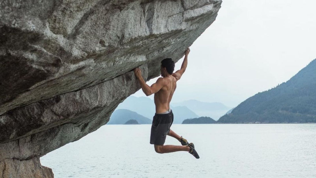 Ryan, a climbing content creator free climbing a rock above water