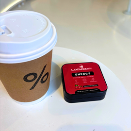 Red locked in energy energy support supplement tin with coffee on white table