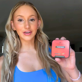 female smiling holding locked in energy supplement in hand