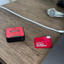 Red locked in energy energy support supplement  tin with energy strip out on a wooden desk with a watch and laptop in the background