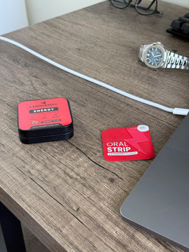 Red locked in energy energy support supplement  tin with energy strip out on a wooden desk with a watch and laptop in the background